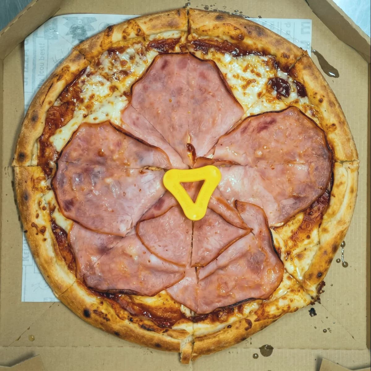 The underbaked ham pizza after re-baking, with an evenly golden crust