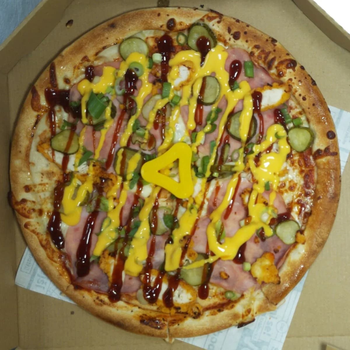 Pizza with lines of cheddar sauce and BBQ sauce